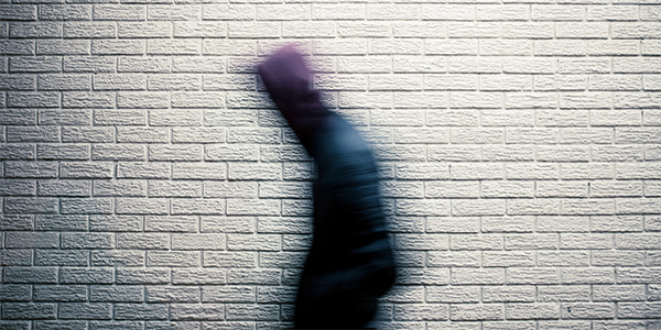 A blurred picture of a person walking past a wall